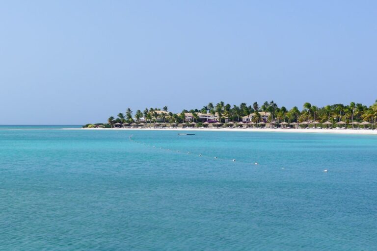 Jumby Bay Island resort buildings and palms viewed across vivid turquoise Caribbean water in Antigua
