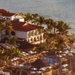 Aerial oceanfront view of One&Only Palmilla with red-roofed resort buildings, pools and rocky Baja coastline