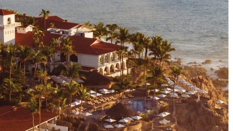 Aerial oceanfront view of One&Only Palmilla with red-roofed resort buildings, pools and rocky Baja coastline
