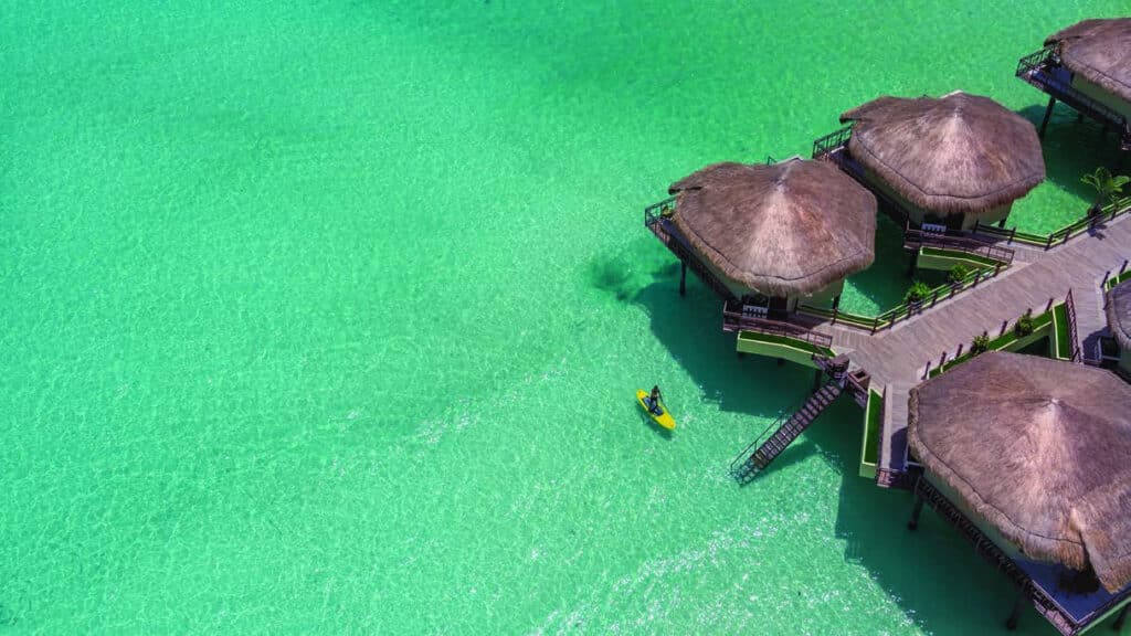 Aerial view of Palafitos Overwater Bungalows above turquoise water at El Dorado Maroma in Riviera Maya