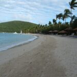 Crescent beach, palm trees, calm blue water and green hills at Rosewood Little Dix Bay on Virgin Gorda