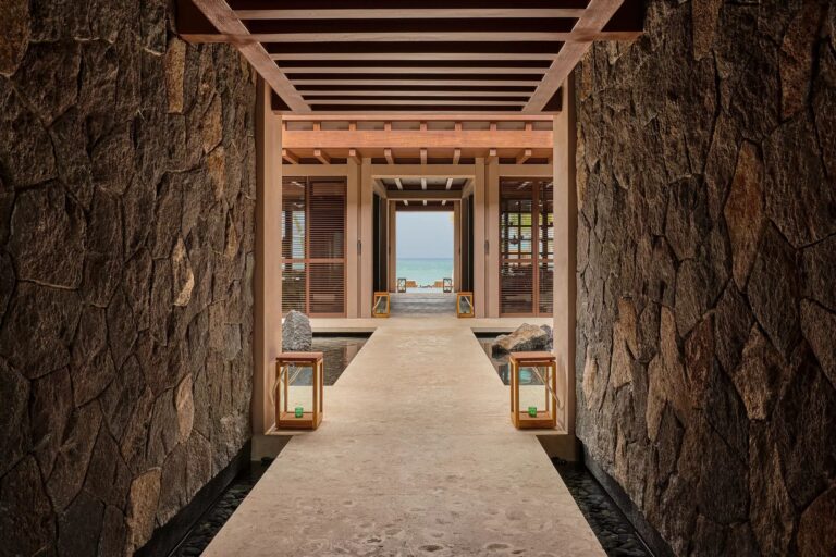 Stone open-air corridor framing water and tropical scenery at Rosewood Mayakoba in Riviera Maya