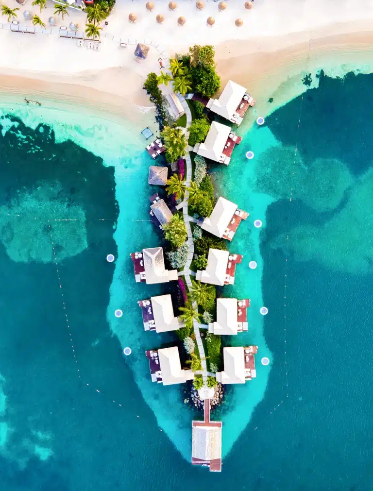 Aerial view of overwater bungalows surrounded by turquoise Caribbean water at Sandals Grande St. Lucian