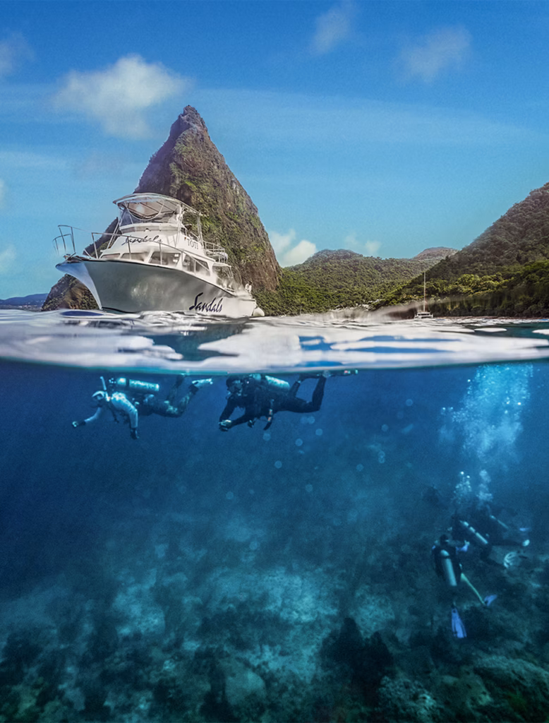 Scuba divers in Saint Lucia beneath a Sandals dive boat with the Pitons in the background