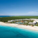 Aerial view of Secrets Maroma Beach Riviera Cancun beside a wide white-sand beach and turquoise water