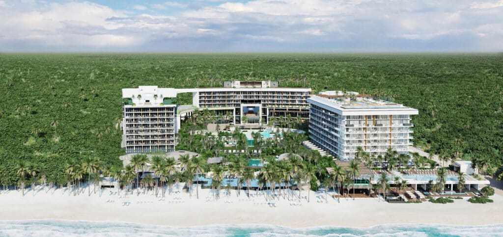 Beachfront view of Secrets Moxché Playa del Carmen with the resort buildings, pools, white sand and Caribbean Sea