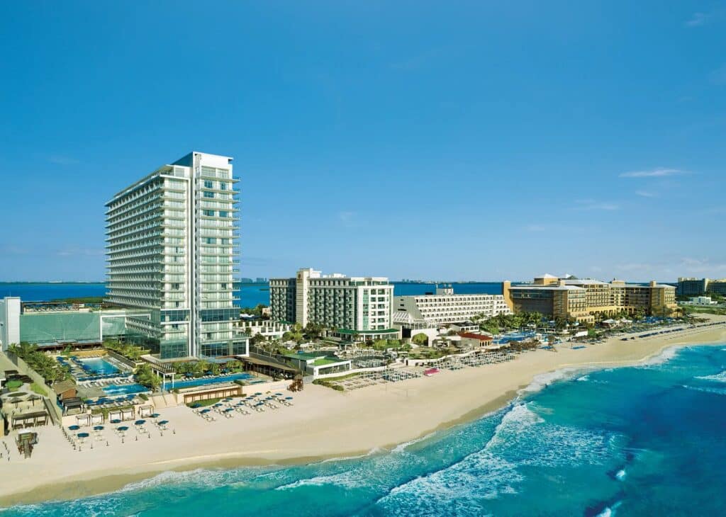 Aerial view of the Secrets The Vine Cancun tower, pools and white-sand beach along the Caribbean Sea