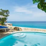Clifftop pool and loungers overlooking bright blue Caribbean water at The Caves in Negril, Jamaica