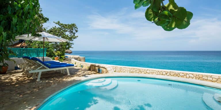 Clifftop pool and loungers overlooking bright blue Caribbean water at The Caves in Negril, Jamaica
