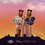 Two attendees holding Disney Believe and Let's Set Sail signs at the reveal event